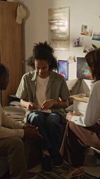 Vertical handheld video of African American young adult male receiving acceptance letter and celebrating with parents. Clip perfect for higher education marketing and student success campaigns