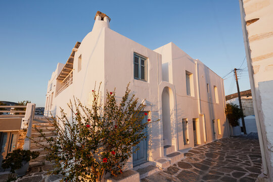 Traditional white Greek residential buildings and houses with blue doors and windows in Paroikia (Parikia) town on Paros island in Greece on a sunny afternoon.
