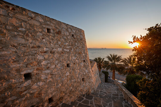 Old stone wall and seascape in Paroikia (Parikia) town on Paros island in Greece at sunset.
