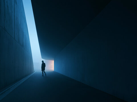 Person Standing in Modern Architectural Passage with Light