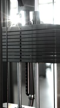 Close-up of a moving weight stack on a cable machine during strength training in a modern fitness gym. Concept of resistance exercise, workout equipment and healthy lifestyle.