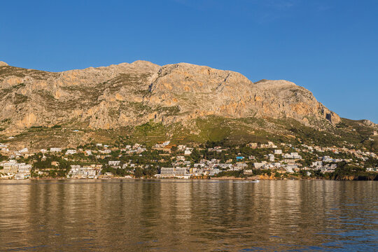 Masouri village on the beautiful and mountainous Kalymnos island by the Aegean Sea in Greece viewed from the sea on a sunny afternoon.