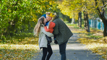 Obraz premium Family embracing, sharing tender moment among fallen golden leaves during autumn park afternoon