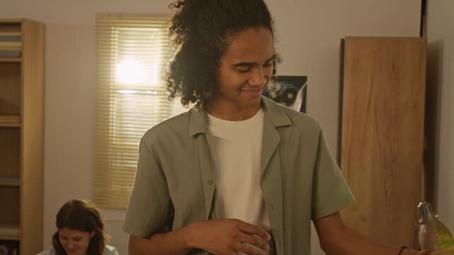 Handheld shot of African American young man packing gold trophy into cardboard box while Caucasian young woman packs suitcase. For relocation services, student housing, or moving company commercials