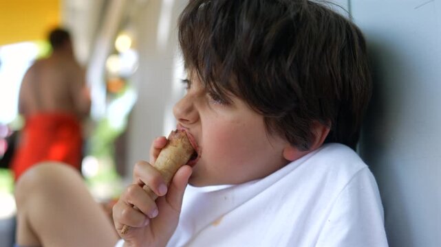 Young boy enjoying chocolate ice cream outdoors, celebrating carefree childhood, summer relaxation and everyday family life