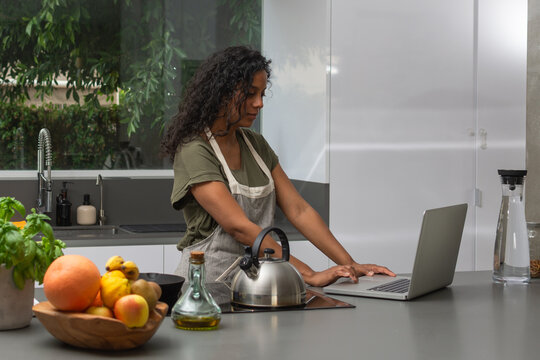 Woman using laptop for meal planning in modern kitchen