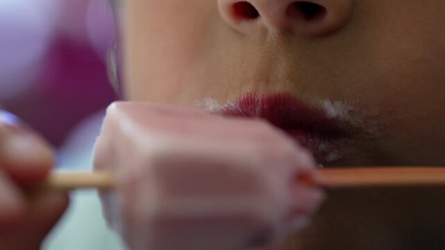 Macro close-up of child eating strawberry ice cream bar, capturing summer refreshment, sweet indulgence and carefree childhood moments