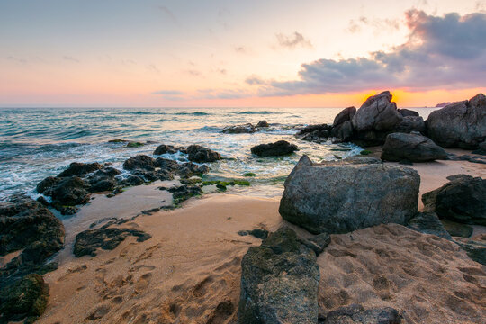 black sea landscape at sunrise. rocks on a sandy beach. sky with clouds glowing in morning light. summer vacation at the sea. bulgaria travel background