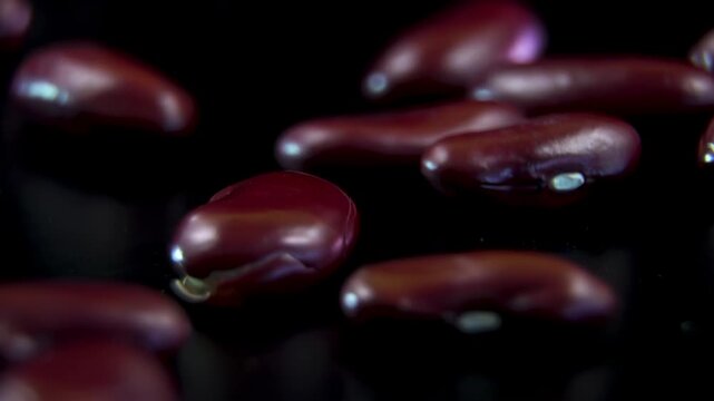 Extreme macro close up of raw red kidney beans heap rotating on dark background, showcasing detailed glossy texture of organic vegan food ingredient
