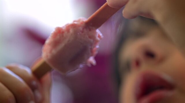 Close-up of child enjoying strawberry ice cream bar, capturing summer refreshment, sweet treats and authentic childhood delight