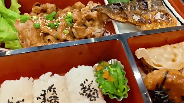 Japanese Bento Lunch Box with grilled teriyaki pork, mackerel fish, rice and seaweed salad, Japan Restaurant Takeout Food Cuisine, Delicacy Variety, Closeup Panning Shot
