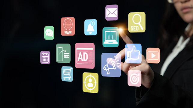 A businesswoman engages with vibrant digital marketing icons in a modern office, showcasing the intersection of technology and business strategy for effective promotion. Fluxor.
