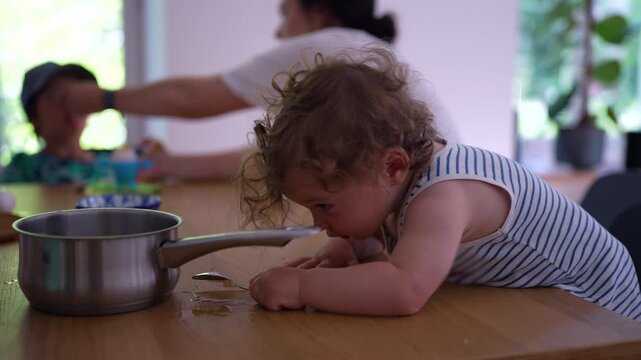 Toddler exploring saucepan on kitchen table, encouraging curiosity, sensory learning and early childhood development