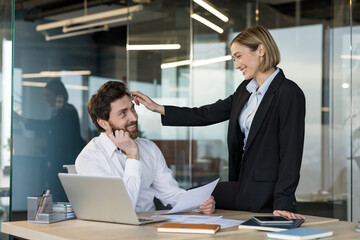 Happy business colleagues engaging in playful professional interaction, a woman gently touching a...