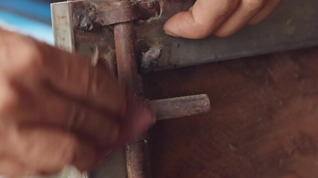 Close-up of hands sanding a rusty metal door hinge with sandpaper for home restoration