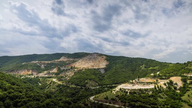 Quarry for extraction of minerals with equipment and machines, and road, in Rhodope Mountains covered with forests