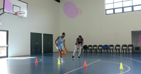 Dribbling male player in blue jersey practicing handling on blue court with cones, basketball hoop © vectorfusionart