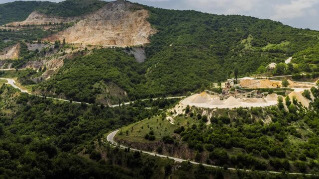 Quarry for extraction of minerals with equipment and machines, and road, in Rhodope Mountains covered with forests