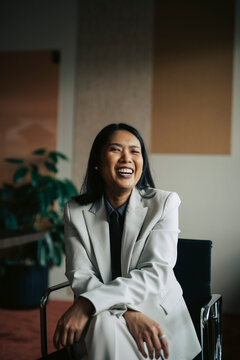 Portrait of happy female financial advisor sitting on chair in modern office