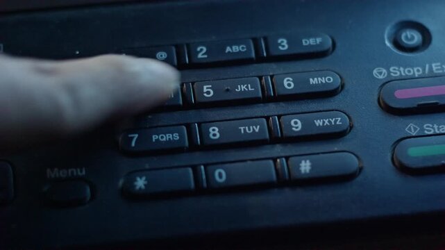 Close-up of a finger pressing numeric buttons on a photocopier machine control panel