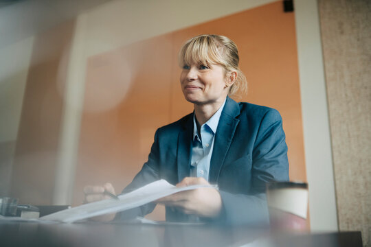 Low angle view of smiling businesswoman holding agreement paperwork
