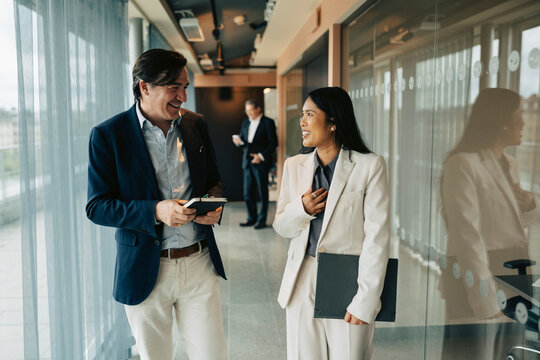 Smiling business partners sharing ideas while moving between office rooms