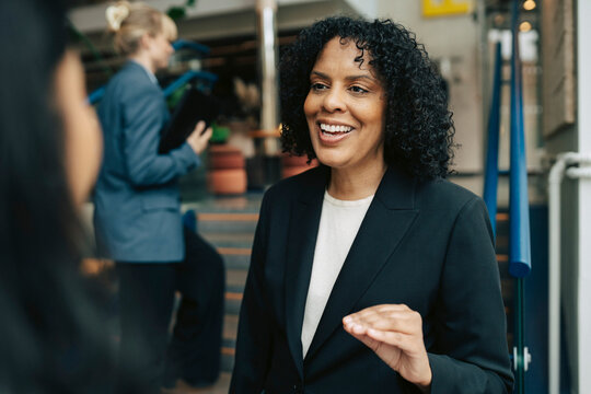 Smiling mature businesswoman having conversation with colleague at office
