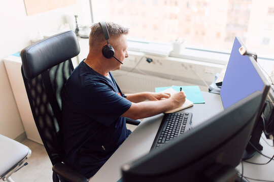 High angle view of doctor writing prescription during video call with patient