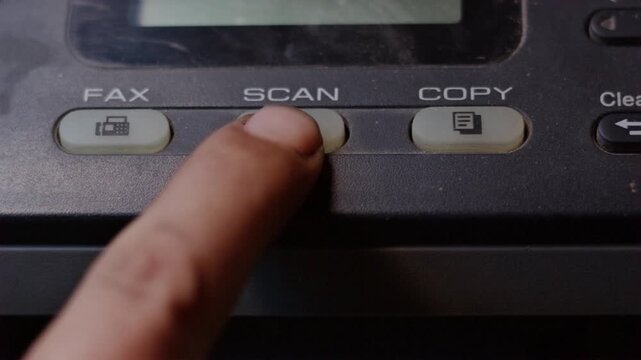 Close-up of a finger repeatedly pressing a scan button on a malfunctioning office machine