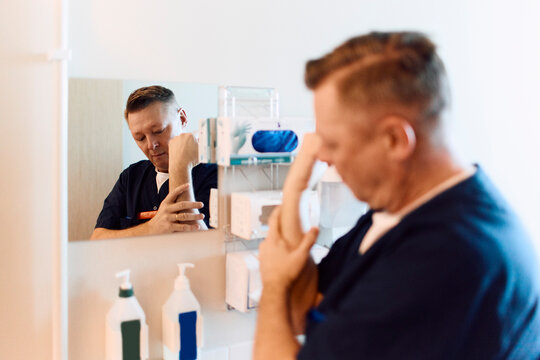 Male medical professional washing hand inside hospital bathroom