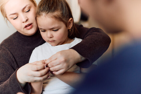 Mother gently holding her daughter's finger during medical test