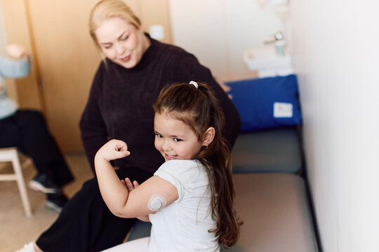 Smiling girl proudly showing her arm muscles while wearing glucose tracking device