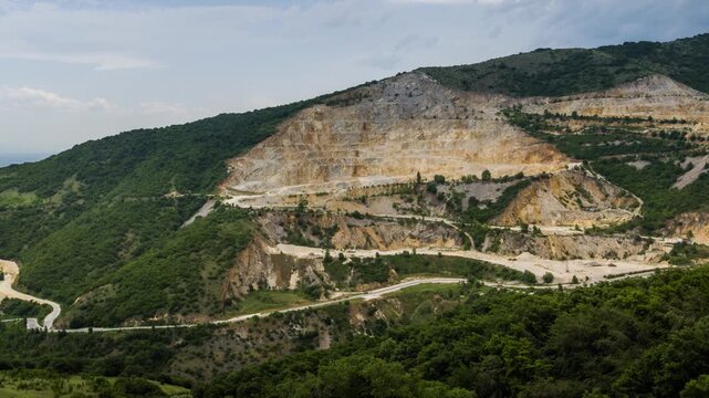 Quarry for extraction of minerals with equipment and machines, and road, in Rhodope Mountains covered with forests