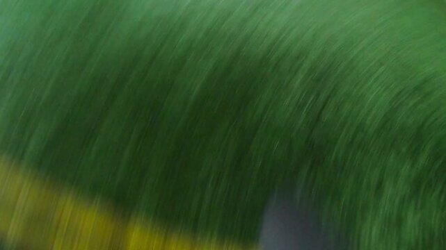 Young soccer player training his skills at football field at evening. Sportsman practicing dribbling ball and kicking it to opponent. Footballer passes the ball to friend. Leisure concept. POV