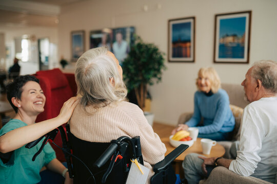 Happy female nurse spending leisure time with senior people at retirement home