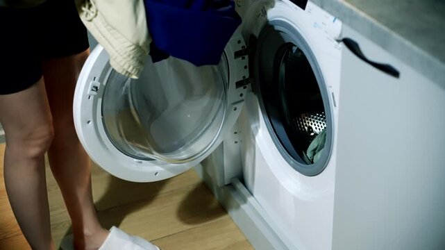 Person Loading Clothes Into Washing Machine Drum. Doing Laundry At Home