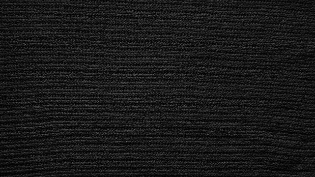 black knitted fabric texture reveals detailed woven wool rows in an elegant minimalist macro view