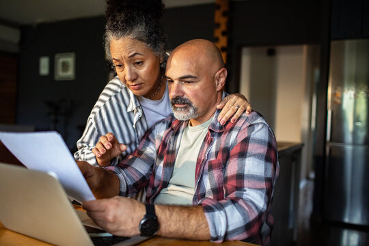 Mature couple reviewing bills on laptop at home