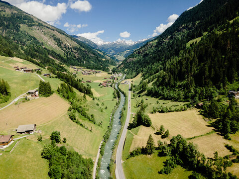 Aerial view of the Moll river winding through the lush green valley with alpine meadows and mountains, Mortschach, Carinthia, Austria.