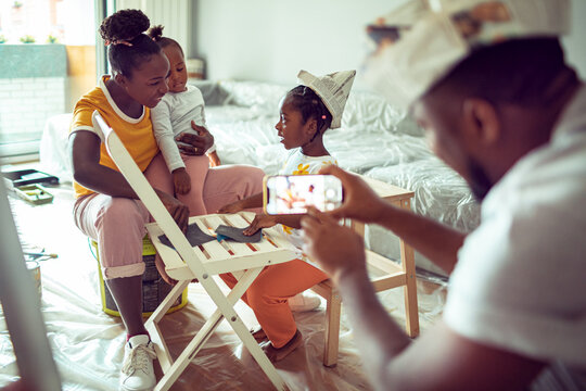 Family renovating bedroom at home, dad photographing children