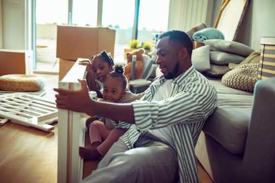 Father assembling furniture with daughters at home