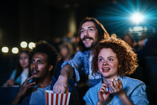 Friends watching movie with popcorn in cinema