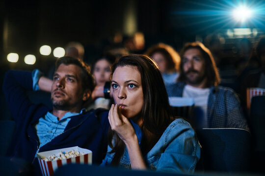 Couple watching a movie and eating popcorn in a cinema