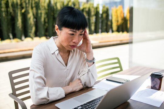 Concerned businesswoman checking laptop at outdoor cafe