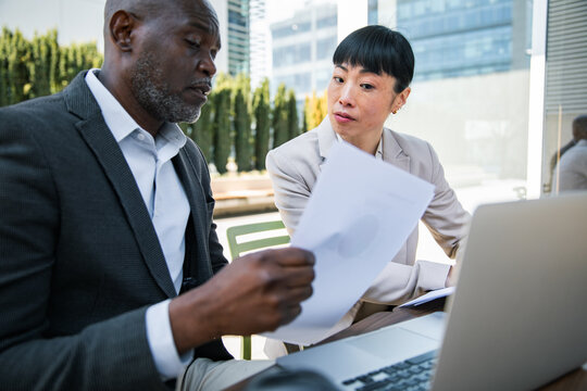 Business colleagues reviewing documents at outdoor meeting