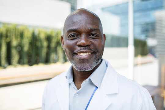 Smiling male doctor portrait outside modern hospital