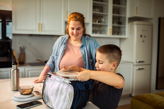 Mother and son packing school lunch in home kitchen