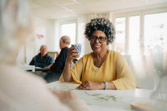 Smiling senior woman socializing with friends while sitting in retirement home