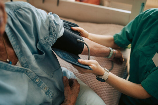 High angle view of female medical professional measuring blood pressure of senior woman
