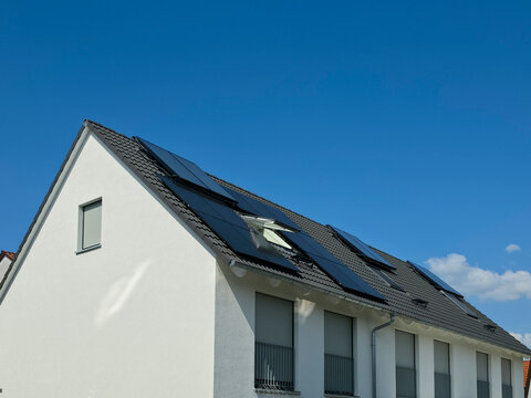 germany, attractive new row house with photovoltaic modules on roof in sunny summer weather reflecting sustainable neighborhood and energy efficient homes